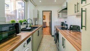 A modern kitchen with wooden countertops, a built-in oven, and a microwave. There is a window providing natural light and a view of the outside.
