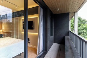 A modern bedroom with a glass partition, a bed, a bedside table, and a mounted TV. - 360 Nato Itaim (São Paulo)