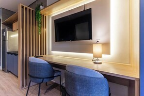 A modern kitchen with a built-in TV, wooden paneling, and a small dining area with two chairs. - 360 Nato Itaim (São Paulo)