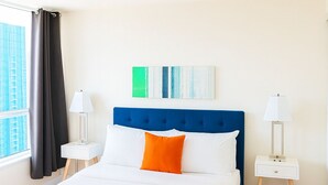 Una camera d'albergo con un letto grande, due comodini, una finestra con tende e vista su un edificio.