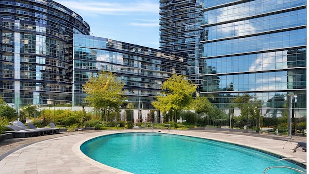 Un edificio moderno con facciata in vetro curvo e piscina con bordo piastrellato.