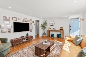 Ein modernes Wohnzimmer mit einem Flachbildfernseher, einer Holzunterhaltungsecke und einem großen Sofa.