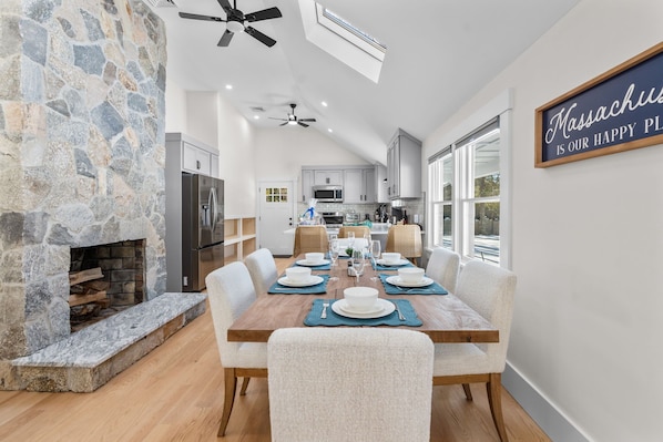 A modern kitchen with stone walls, a dining area with a wooden table set for six, and a kitchen island.