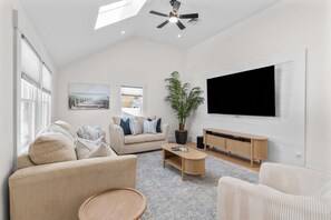 A modern living room with a sofa, coffee table, and a large TV on the wall.