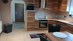 A modern kitchen with wooden cabinets, a microwave, oven, and a dining area with a table and chairs. - NEW! Modern living in Erbendorf - Upper Palatinate (Erbendorf)