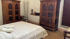 Une chambre à coucher avec un lit, des armoires en bois, une petite étagère et une fenêtre.