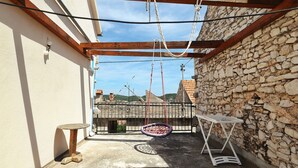 Un pequeño patio al aire libre con una silla colgante, una mesa y un muro de piedra.
