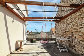 A small outdoor patio with a hanging chair, a table, and a stone wall. - Holiday Home Tranquilla With Heated Pool (Blato)