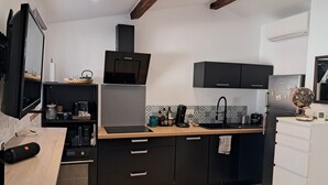 Eine moderne Küche mit schwarzen Schränken, einer Holz Arbeitsplatte, einem eingebauten Ofen und einer Mikrowelle.