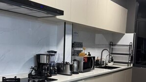 Et moderne køkken med hvide skabe, komfur i rustfrit stål, indbygget ovn og en bordplade i sort.