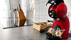Una encimera de cocina con un electrodoméstico rojo, un utensilero de madera y un recipiente negro con alimentos.