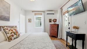 Un dormitorio con cama, cómoda y televisor en la pared.