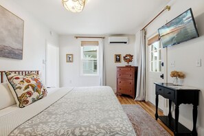 A bedroom with a bed, dresser, and a television on the wall. - Boothbay Harbor King Suite  - Room 13 at AQ Inn - Fireplace, Patio, Harbor View! (Boothbay Harbor)