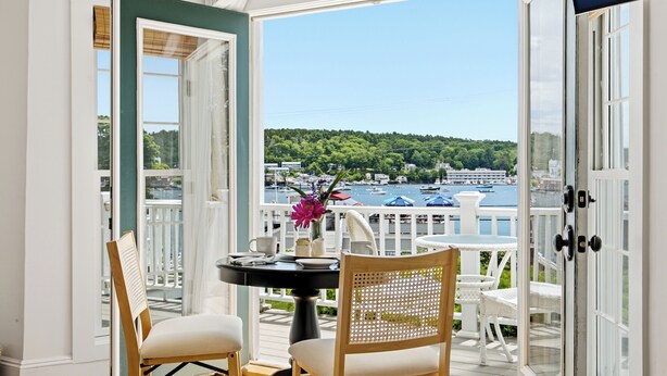 A balcony with a table and chairs, a view of a marina, and a white fence. - Boothbay Harbor King Suite  - Room 13 at AQ Inn - Fireplace, Patio, Harbor View! (Boothbay Harbor)