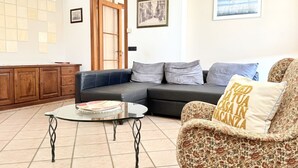 Ein Wohnzimmer mit einer Couch, einem Couchtisch, einem gemusterten Sessel, einer Holzkabine und einer Tür.