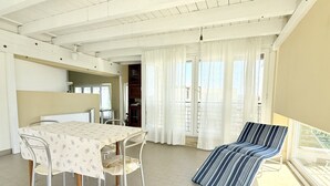 Ein Zimmer mit Esstisch, Stühlen, einem gestreiften Lounge-Sessel und einem Balkon mit Blick.
