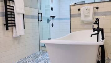 A modern bathroom with a freestanding bathtub, a glass shower enclosure, and a separate sink area.