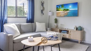 A modern living room with a grey sofa, a round coffee table, and a bookshelf. - Unit 4 - Beautiful 1BR Apt w/Parking Near Biscayne Boulevard (Miami)