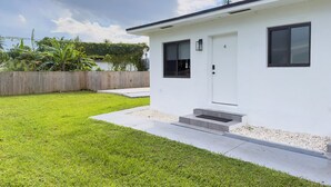 A modern white house with a front door, a small porch, and a fenced backyard. - Unit 4 - Beautiful 1BR Apt w/Parking Near Biscayne Boulevard (Miami)