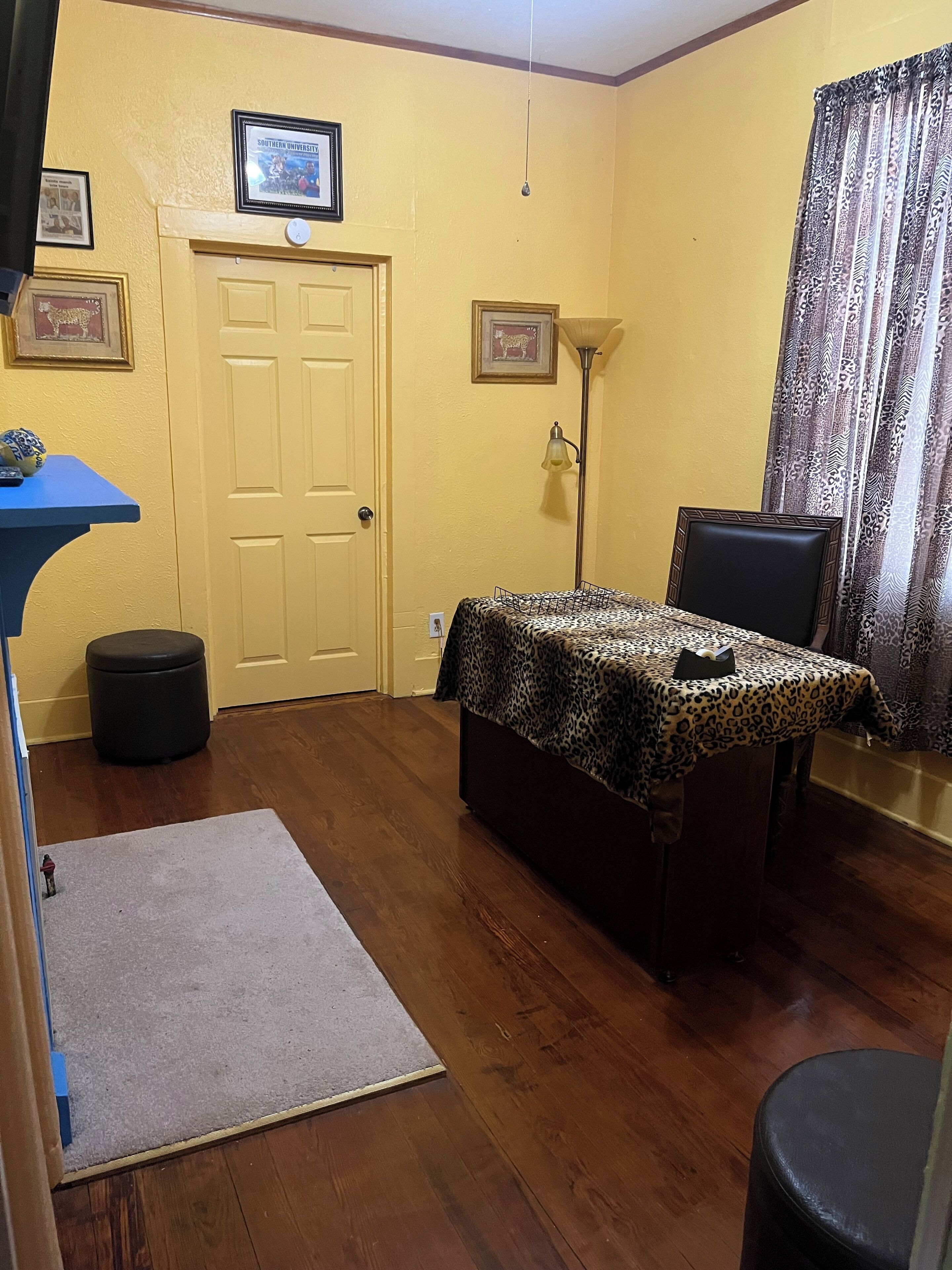 A room with a bed, a desk, a chair, a lamp, and a door.