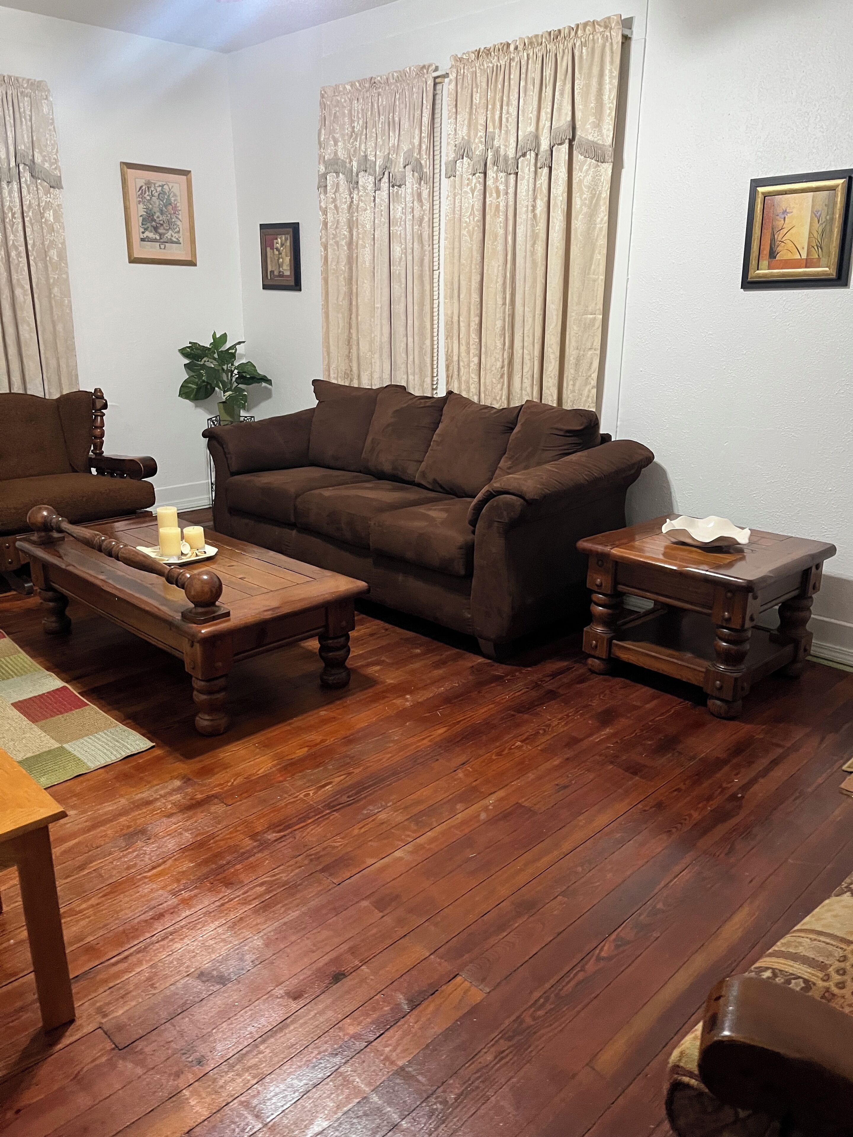 Un salon avec un canapé marron, une table basse en bois et une petite table d’appoint.