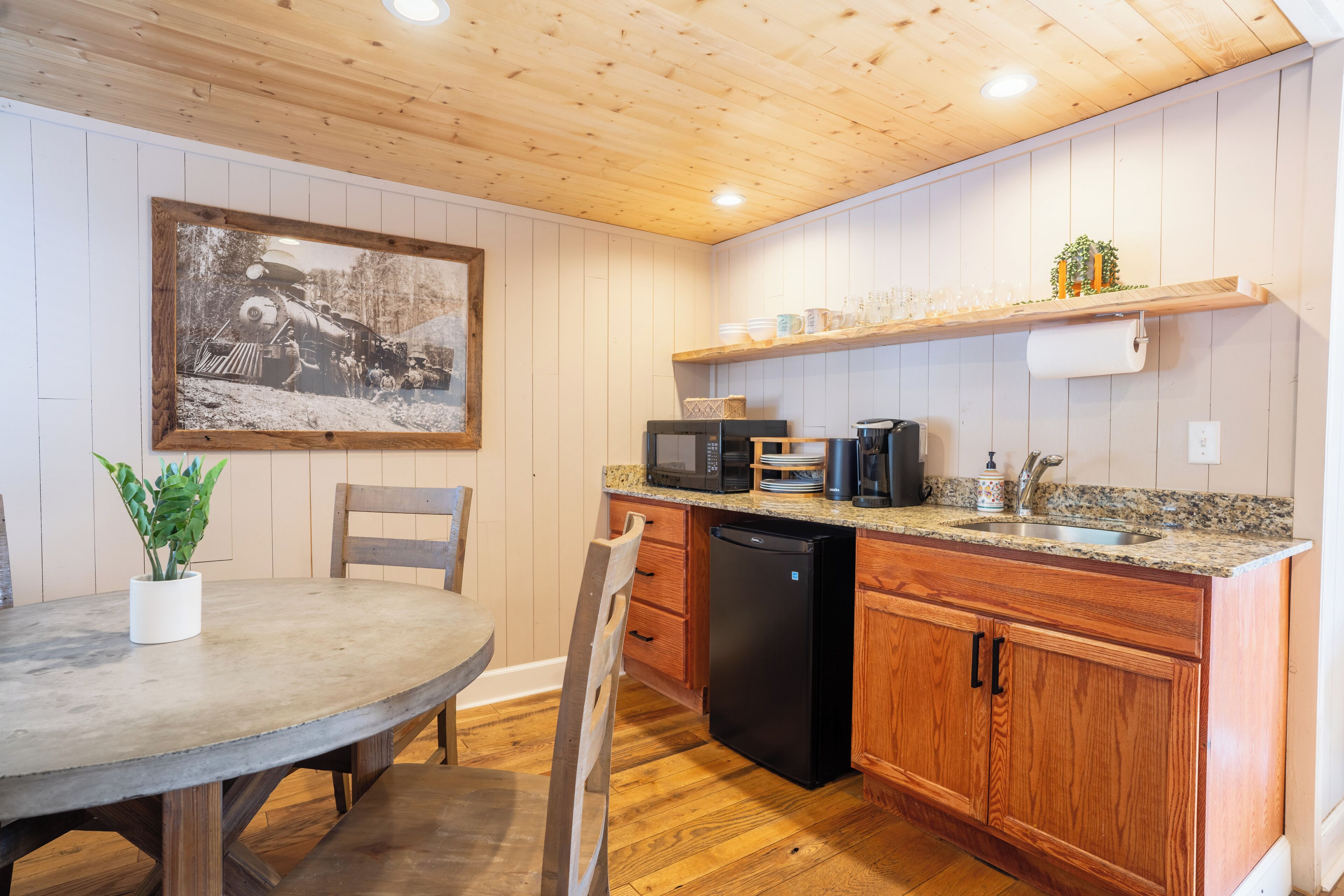 A kitchen with wooden cabinets, a granite countertop, a microwave, a coffee maker, and a sink.