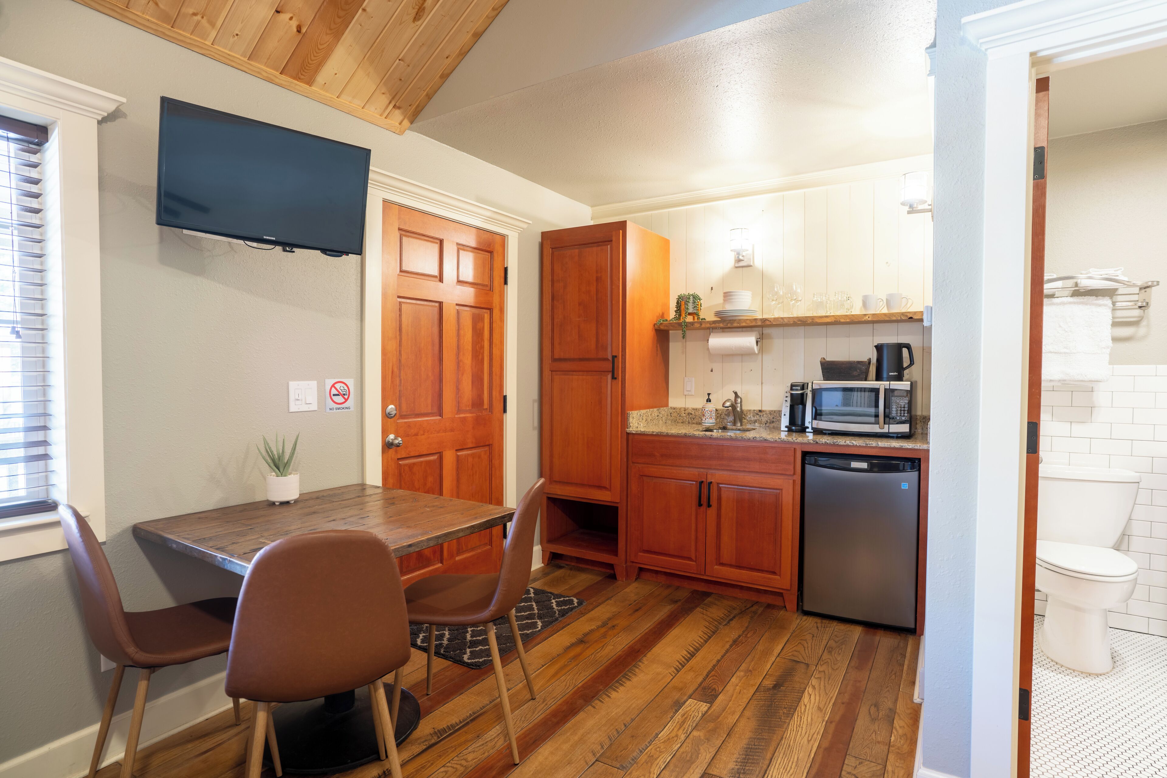 A compact kitchen with wooden cabinets, a built-in microwave, and a dishwasher.