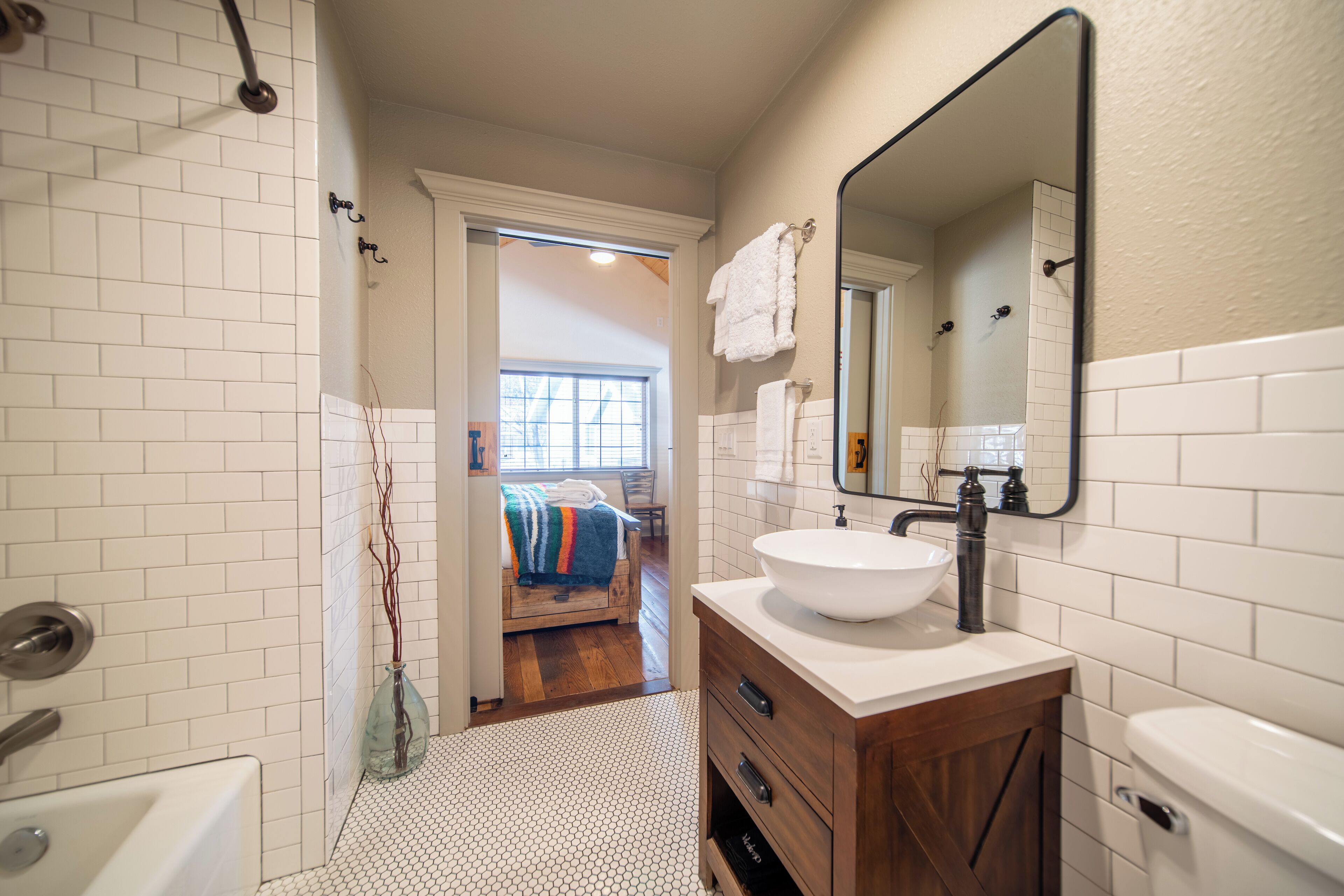 A bathroom with a white sink, wooden vanity, and a large mirror.