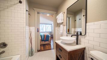 A bathroom with a white sink, wooden vanity, and a large mirror.