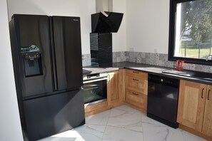 Eine moderne Küche mit einem schwarzen Kühlschrank, einem eingebauten Backofen und einem Geschirrspüler.