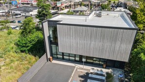 A modern building with a flat roof, large windows, and a parking area with a handicap accessible space.