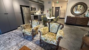A modern kitchen with grey cabinets, stainless steel appliances, and a dining area with patterned chairs and a round table.