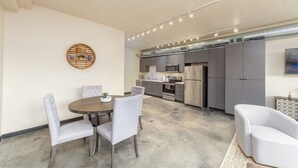 Una cucina moderna con mobili grigi, elettrodomestici in acciaio inossidabile e zona pranzo con tavolo rotondo e sedie rivestite di grigio.
