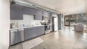 Una cucina moderna con mobili grigi, elettrodomestici in acciaio inossidabile e un'ampia finestra che garantisce luce naturale.