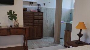 Ein Schlafzimmer mit einem Bett, einer Holzkommode und einem Schreibtisch mit Lampe.