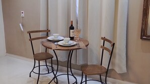 Ein Essbereich mit einem runden Tisch, zwei Stühlen, einer Weinflasche und einem Glas.