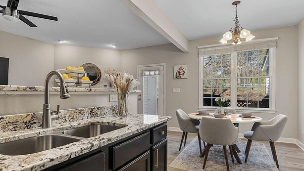 A kitchen with a granite countertop, black cabinets, and a dining area with a table and chairs. - Beautiful Townhouse located between Raleigh & Cary (Raleigh)