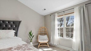 A bedroom with a bed, a window with curtains, a chair, and a potted plant. - Beautiful Townhouse located between Raleigh & Cary (Raleigh)