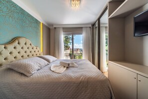 Una habitación de hotel con una cama grande, un televisor en la pared y un balcón con vistas.