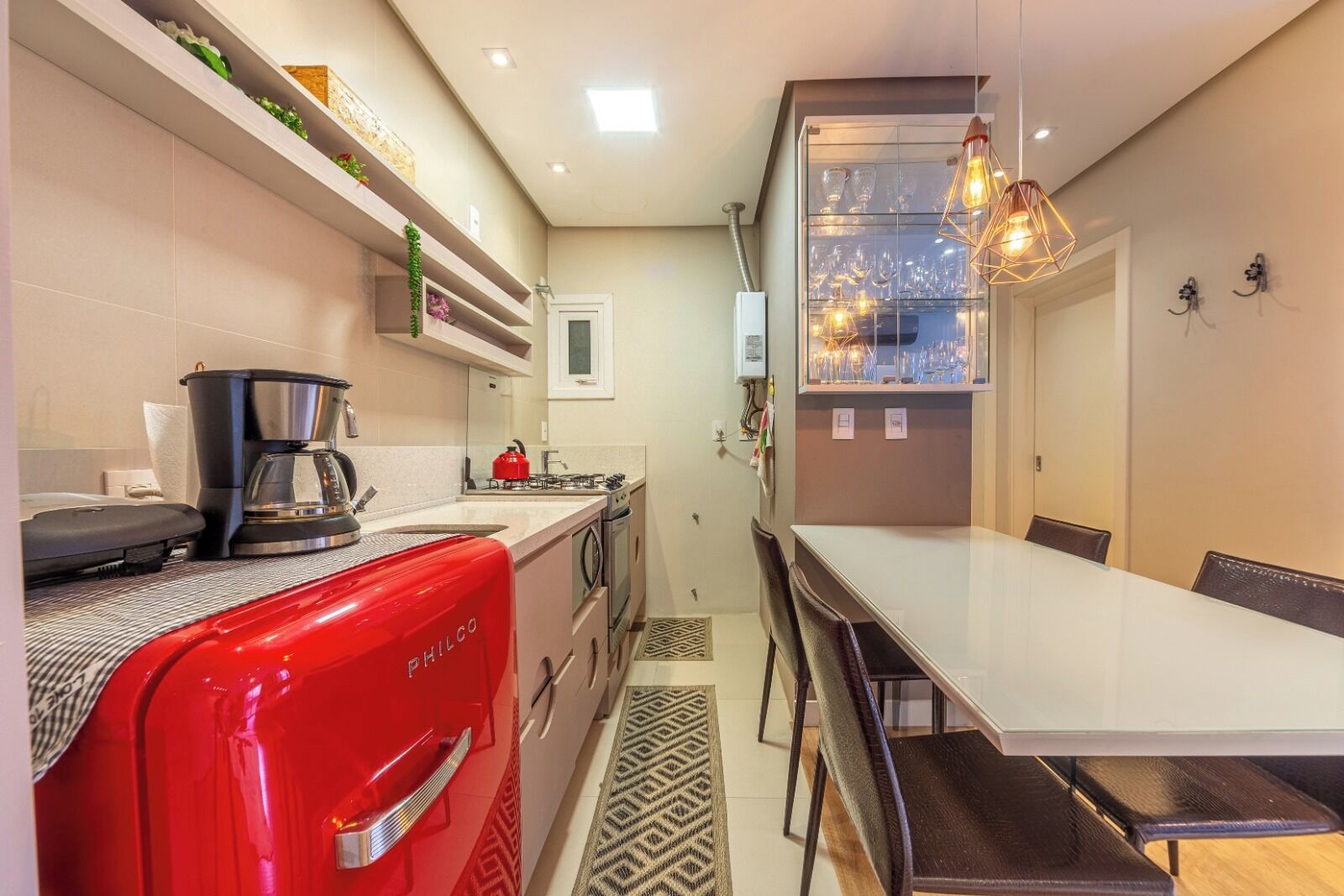 A compact kitchen with a coffee maker, a red appliance, and a dining area with a table and chairs.