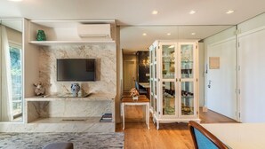 Un salon moderne doté d’une cheminée en marbre, d’un téléviseur à écran plat, d’un meuble avec des portes en verre et d’une table à manger en bois.