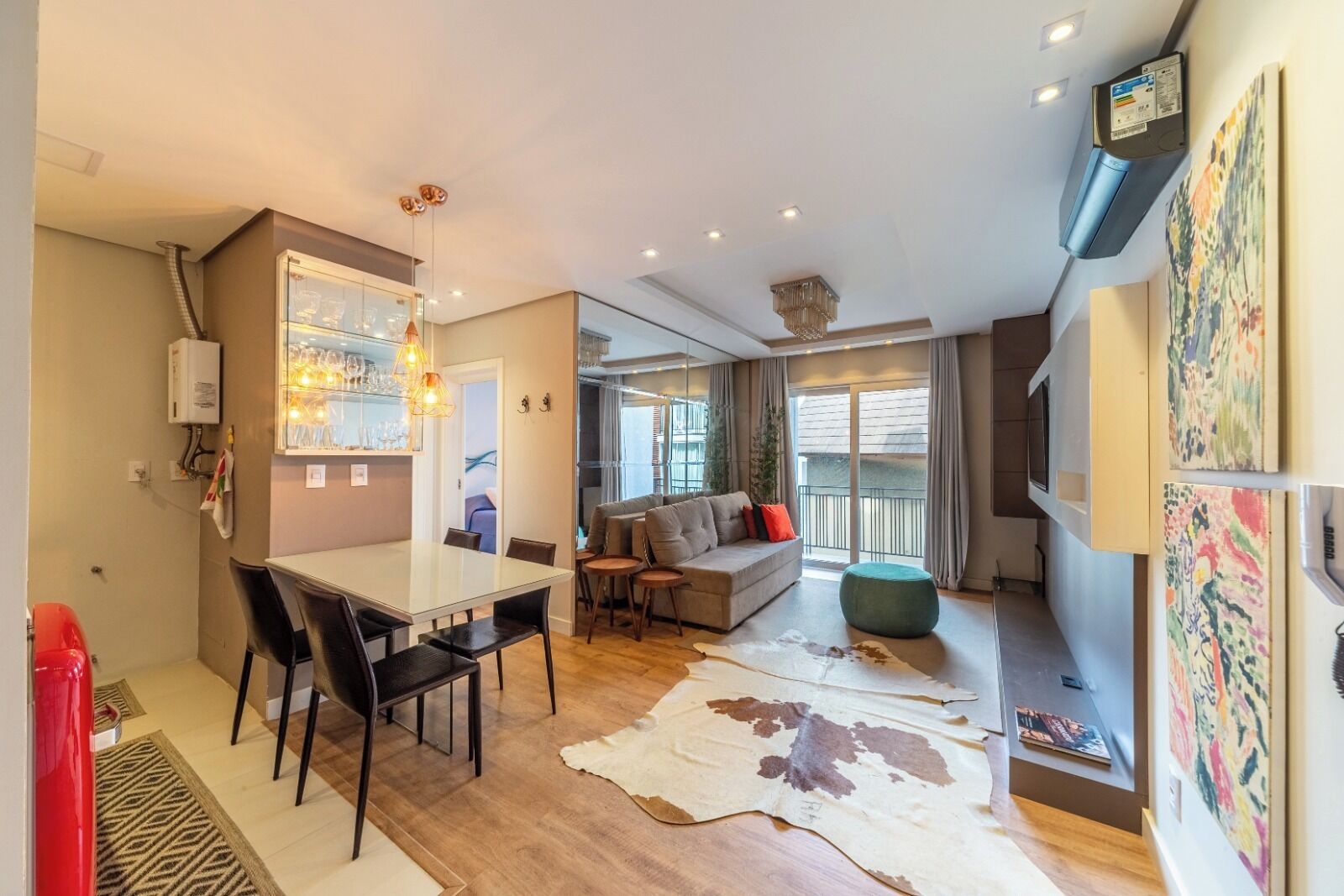 A modern living room with a sofa, a dining table with chairs, a large window, and a ceiling fan.