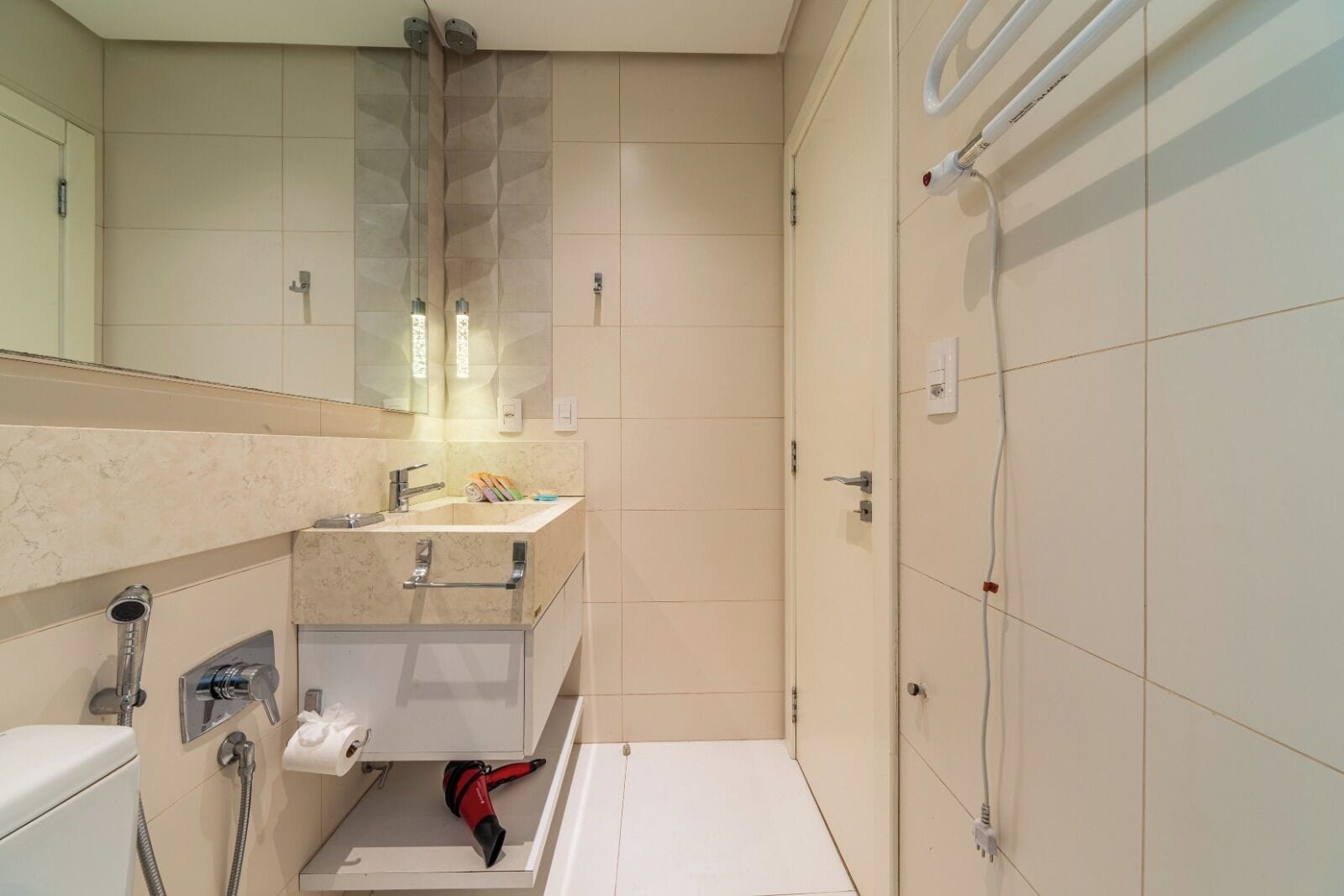 Un baño con inodoro, lavamanos, espejo, toallero y ducha.