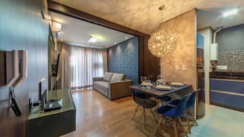 Una habitación de hotel moderna con comedor, sofá, televisor y cocina.