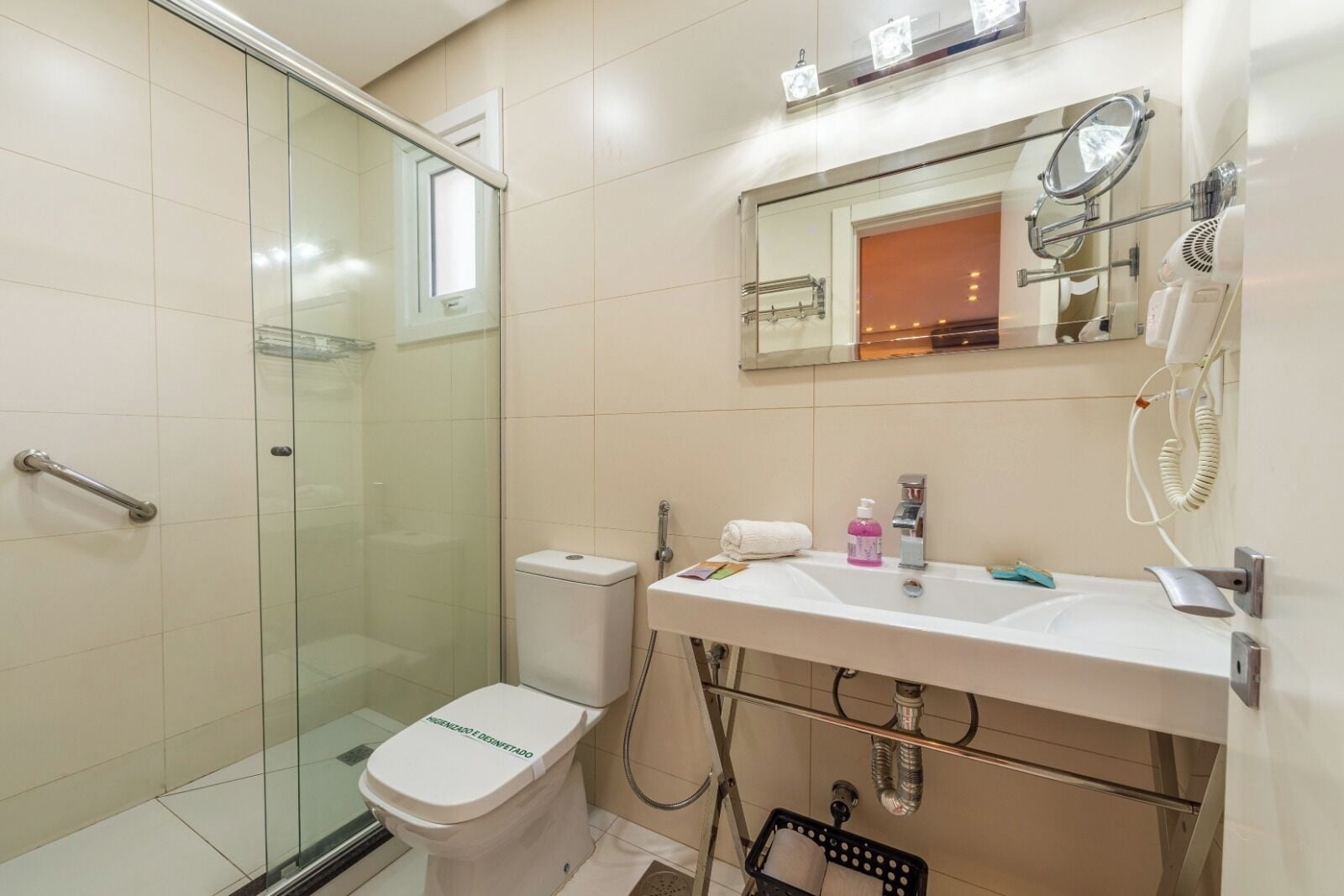 Une salle de bain avec une douche à parois de verre, des toilettes, un lavabo avec un miroir et un sèche-cheveux.