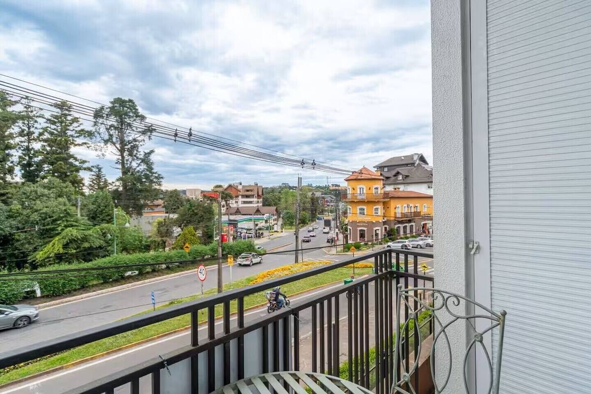 A balcony overlooking a street with buildings, a speed limit sign, and a pedestrian crossing.