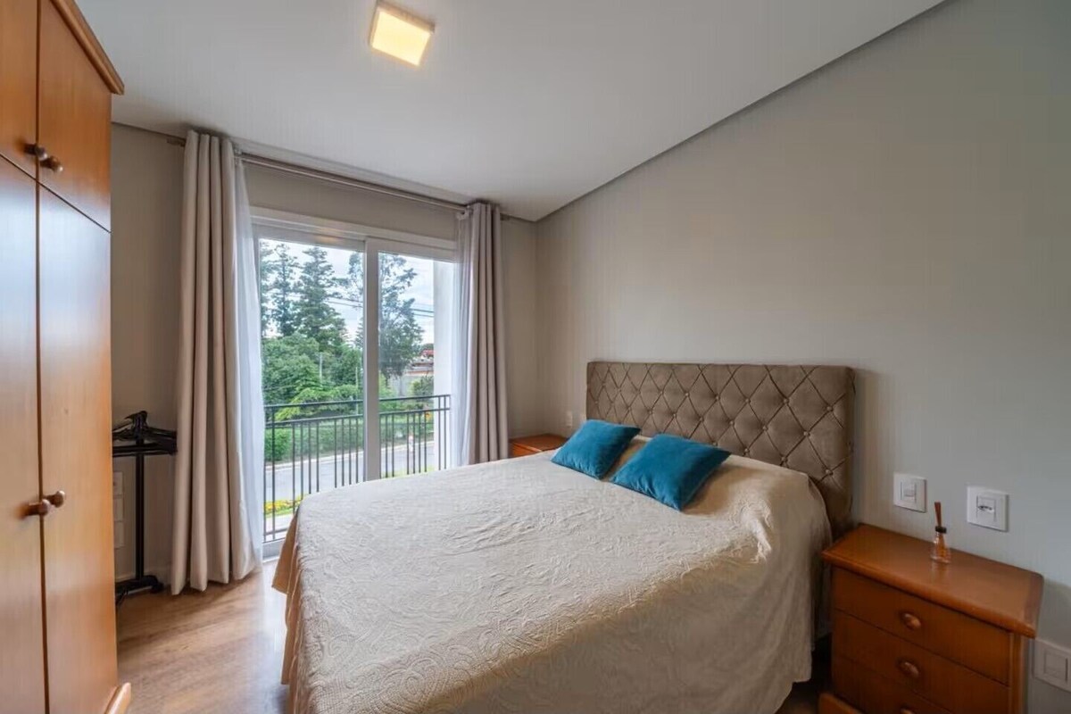 Una camera da letto con un letto grande, una testiera, un comodino, un armadio e vista sull'esterno attraverso una finestra.