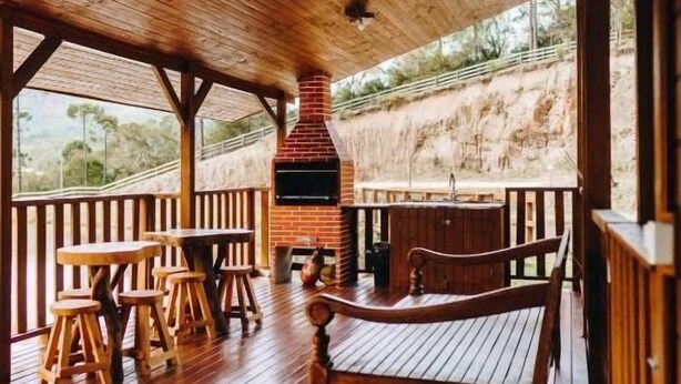 Een houten terras met een metselwerk open haard, houten banken en tafels.
