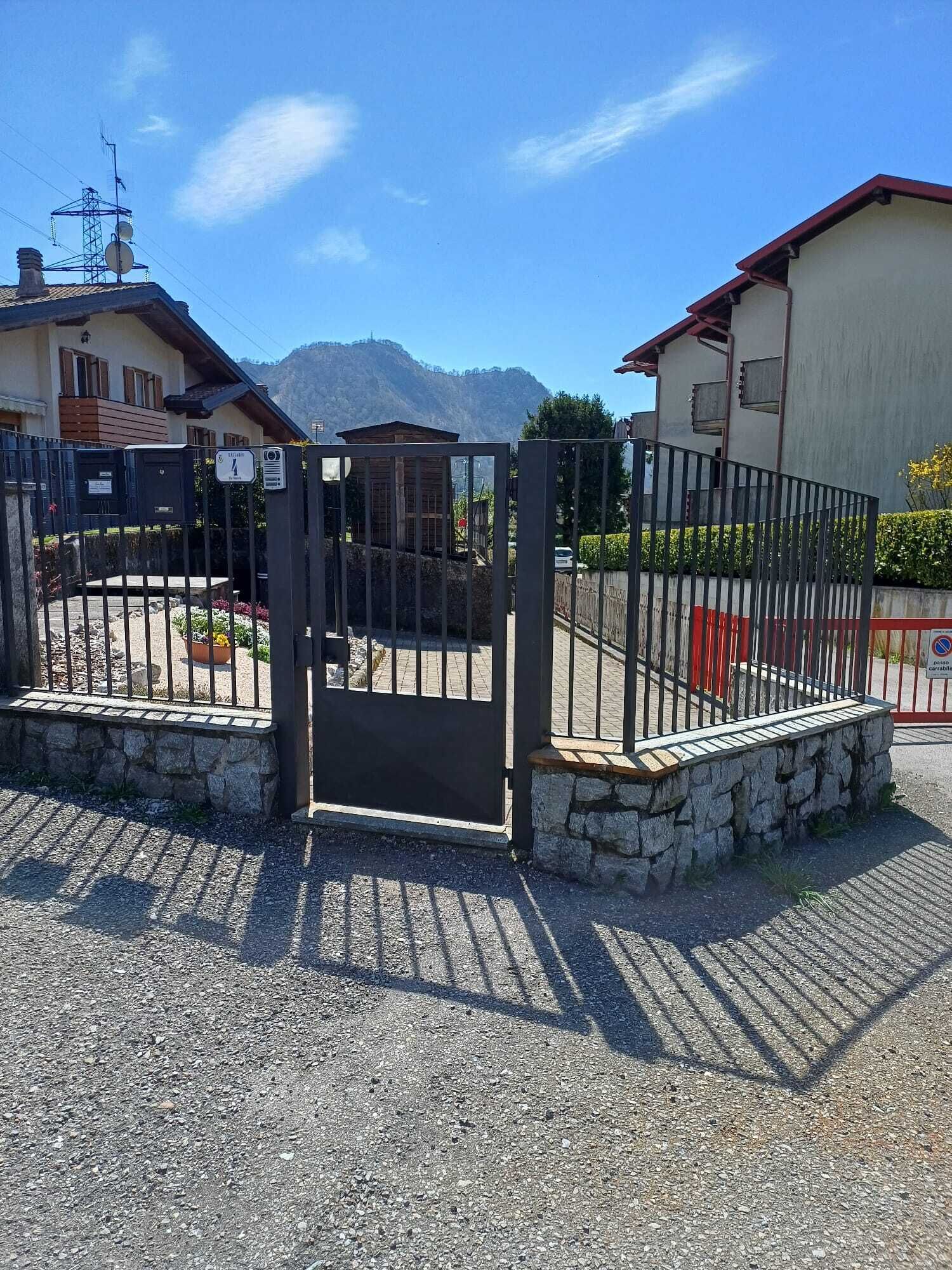 Ein verschlossener Eingang mit einer Steinmauer und einem Metallgitter, vor strahlend blauem Himmel.