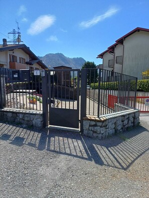 A gated entrance with a stone wall, a metal gate, and a clear sky. - RED HOUSE (Ballabio)